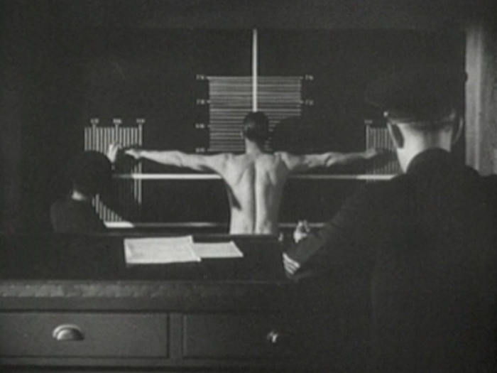 This is from when Kent enters the prison. It's coldly casual as he's stripped and every inch is measured. The man in the foreground 