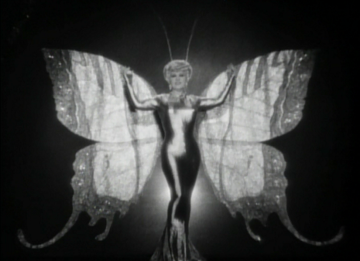 West's introduction to the movie is showing her as a woman who is wildly popular for, uh, posing in front of backgrounds and looking like things. I guess that's pretty... uh... something.